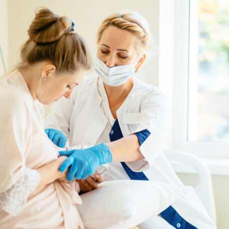 O femeie care este ajutată de un consultant în alăptare să atașeze bebelușul la sân